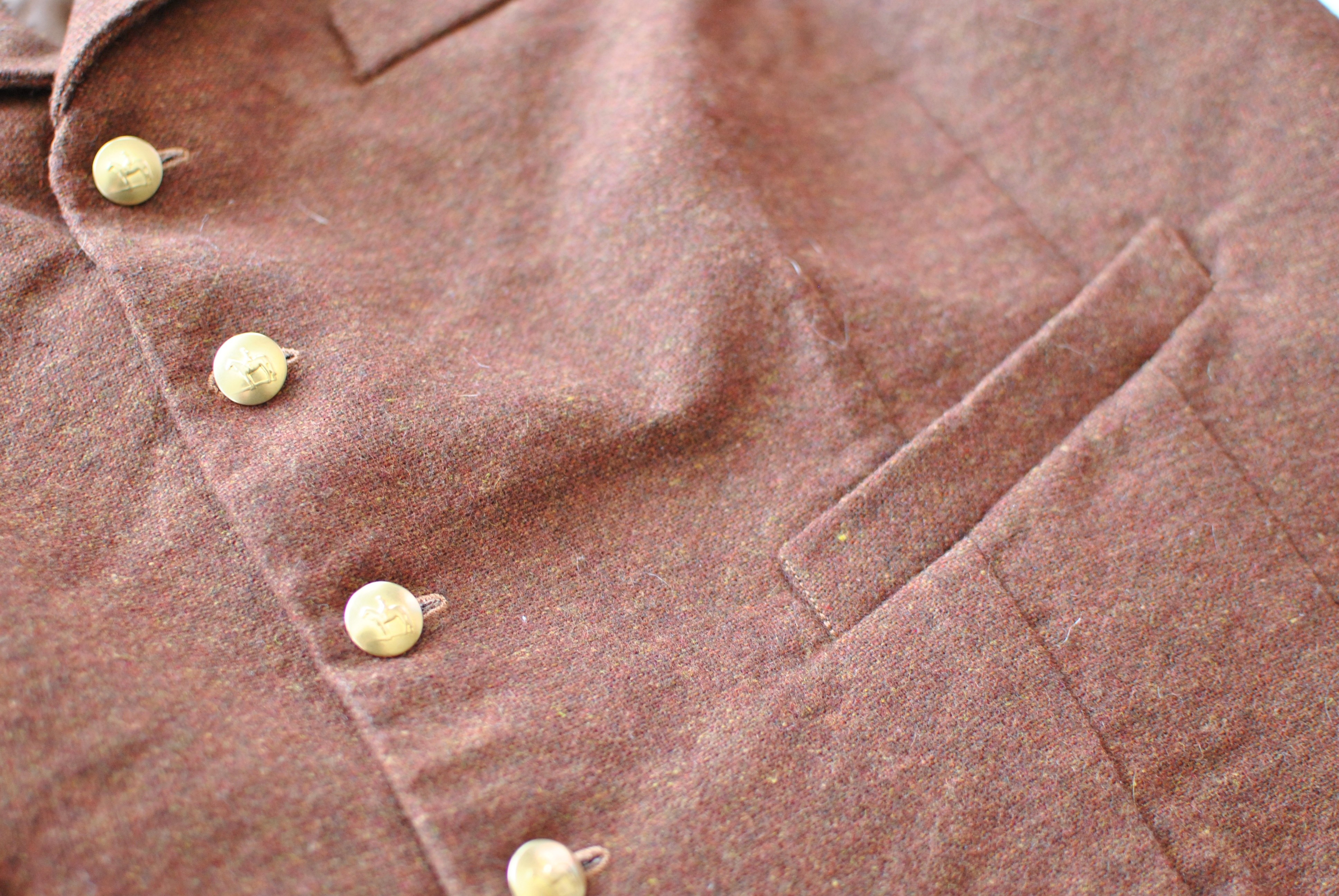 A close up of the vest, showing gold buttons and a welt pocket.